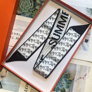 Detail of a black and white pony print silk twilly scarf in a luxury orange gift box