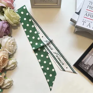 Dettaglio della sciarpa a pois verdi con calligrafia Paris France e bordo geometrico