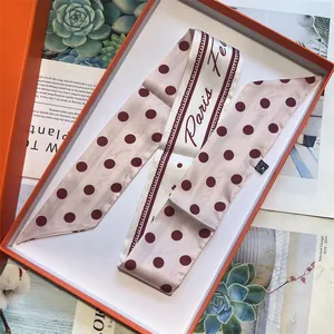 Twilly in seta rosa a pois con scritta Paris in una confezione regalo arancione