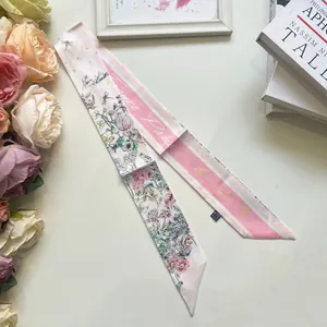 Dettaglio di un elegante foulard Twilly in seta con motivi floreali e righe rosa