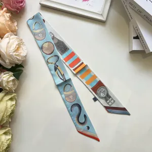 Détail d'un foulard en soie bleu clair avec motifs peints à la main de cadenas et montres