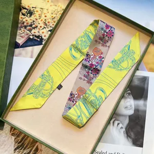 Vista detallada de pañuelo de seda floral con cadena ecuestre en caja de regalo verde