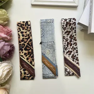 Detail shot of three printed silk-like twilly scarves with leopard and floral patterns