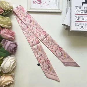 Close-up of pink floral satin scarf with France Paris text and tulip patterns on white desk