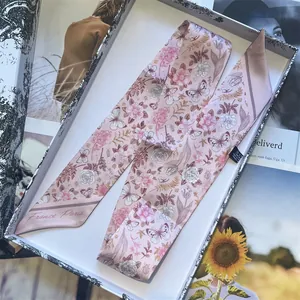 Pink floral silk skinny scarf with butterfly prints in a white gift box on a magazine