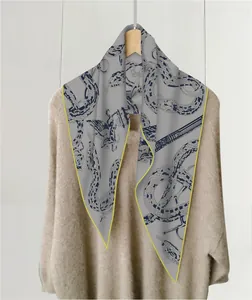 Detalle de pañuelo gris con estampado de serpiente azul y bordes amarillos en contraste