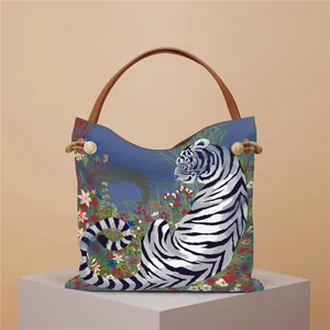 Detail view of blue tiger and floral print tote bag with brown woven handle accents