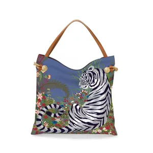 Blue tote bag featuring a white tiger and floral art with brown leather handles