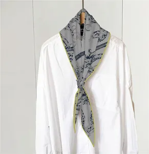 Detalle de bufanda gris con estampado de serpiente azul anudada sobre una camisa