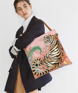 Detail of a pink tote bag featuring a tiger and floral print with leather straps