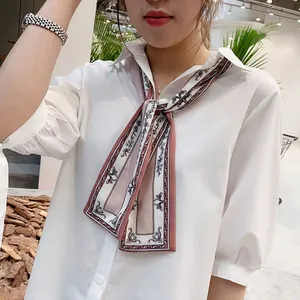 Close-up of a floral print satin scarf styled with a white shirt in a chic indoor setting