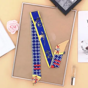 Detail of skinny silk scarf with royal blue horse carriage print on a metal tray
