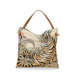 Detail of artistic tiger print tote bag with brown leather handles and metal rivets