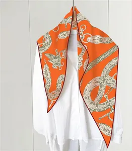 Detalle de bufanda de seda con estampado de pitón naranja y acabado de dobladillo rojo