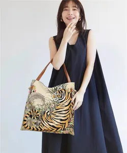 Detail of tiger print tote bag featuring leather shoulder straps and decorative rope