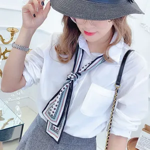 Detail of a geometric print twilly scarf tied on a white shirt collar for women