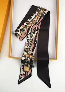 Detail of leopard print twilly silk scarf with gold chains in premium orange box
