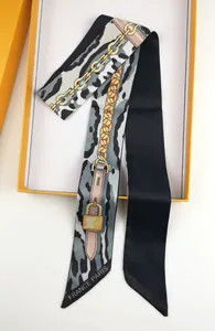 Detail of a leopard print silk scarf with chain patterns inside an orange gift box