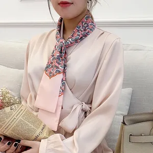 Detail of pink paisley silk-like scarf tied around the neck with an elegant floral pattern