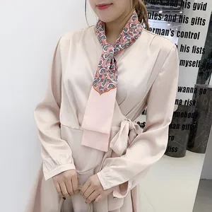 Close-up of champagne satin wrap dress featuring a detailed paisley print silk scarf