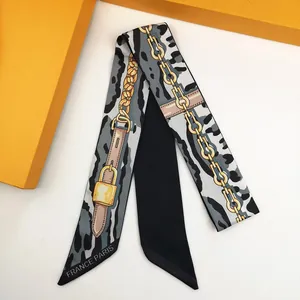 Detailed view of silk twilly with animal print and golden chain motifs on orange gift box