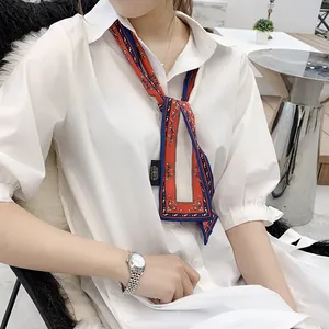 Close-up of a tied retro print satin scarf in red and blue on a white shirt