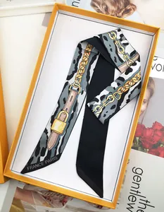 Detail of silk scarf with chain print and leopard pattern in an orange gift box