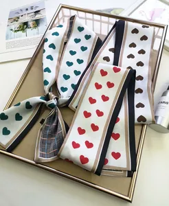 Detail view of heart-print long silk scarves with classic plaid patterns in elegant gold frames