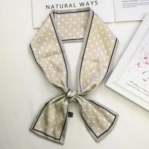 Detailed view of beige polka dot twilly silk scarf with navy blue border and wash label