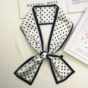 Detailed shot of white satin scarf with black polka dots tied next to fashion book