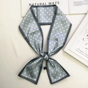Detail of blue polka dot silk scarf tied on a white surface with minimalist props