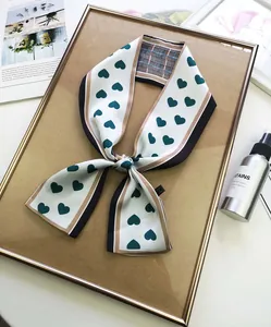 Detail of elegant white twilly scarf with green hearts and colorful contrast borders