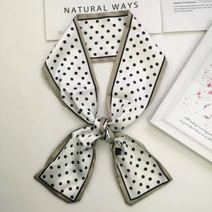 Detailed view of polka dot silk scarf with khaki borders on a minimalist background