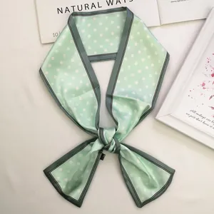 Detail of mint green polka dot silk scarf tied in a bow with magazine background