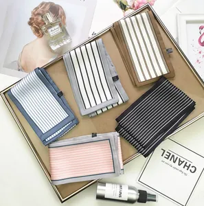 Detailed flat lay of five striped satin skinny scarves in soft pastel colors in a tray