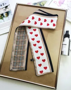 Detail of double-sided silk twilly with red heart pattern and classic plaid texture