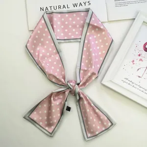 Detailed view of pink polka dot silk scarf tied in a bow on minimalist background