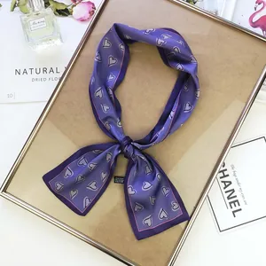 Detail of purple silk scarf with heart patterns and black label inside a gold frame