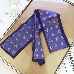 Detail of a purple narrow silk scarf with heart patterns on a golden frame display
