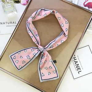 Detail of pink satin twilly scarf with heart patterns on a stylish wooden display