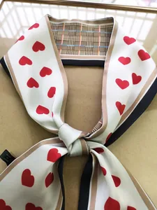 Detail of a double-sided Twilly scarf with red heart patterns and a classic plaid design
