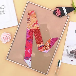Dettaglio di un foulard twilly in seta floreale con rose rosa e accessori alla moda