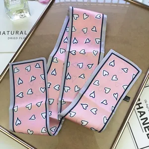Detailed view of pink narrow scarf with heart pattern on a decorative background