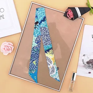 Dettaglio di un foulard in seta blu per borse su un vassoio in oro rosa