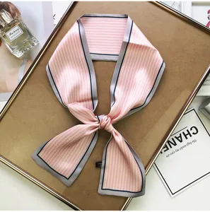 Detail of pink and white striped skinny scarf with black trim on a wooden tray
