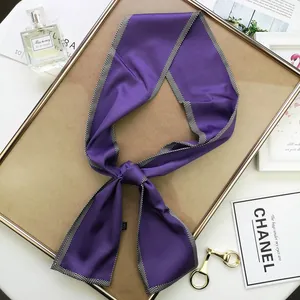 Détail d'un foulard en soie violette avec bordure à chevrons sur cadre doré