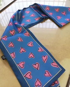 Macro detail of 100% silk skinny scarf showing pink heart pattern and high-quality hem