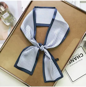 Detailed shot of striped narrow scarf featuring blue and white silk texture and brand tag