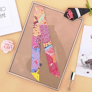 Dettaglio di un foulard twilly in seta con stampa colorata di cervi e motivi floreali