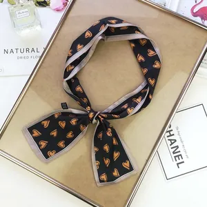 Detail of a black skinny scarf with orange hearts tied in a bow on a decorative frame
